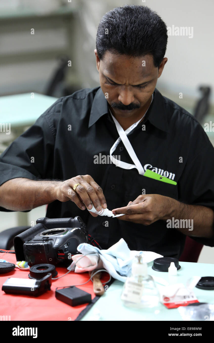 Dubai, United Arab Emirates, an employee of Canon Professional Service cleans an SLR Stock Photo