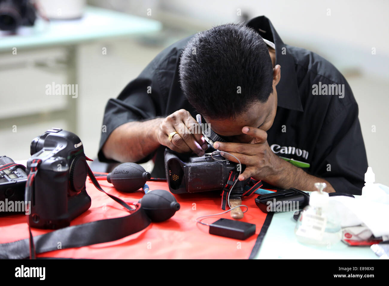 Dubai, United Arab Emirates, an employee of Canon Professional Service cleans an SLR Stock Photo