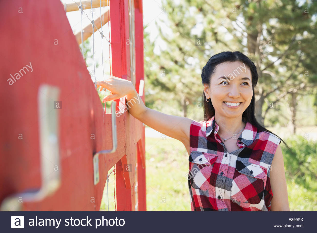 Smiling woman leaning on fence in garden Stock Photo