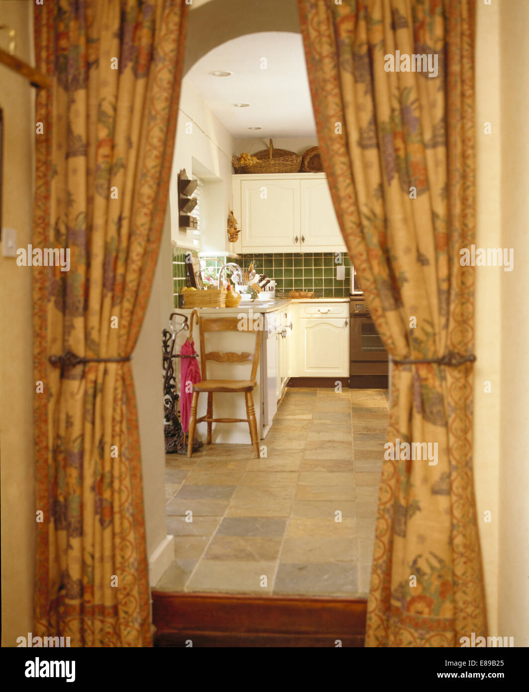Patterned Curtains On Doorway To Dated Country Kitchen With Vinyl Stock Photo Alamy
