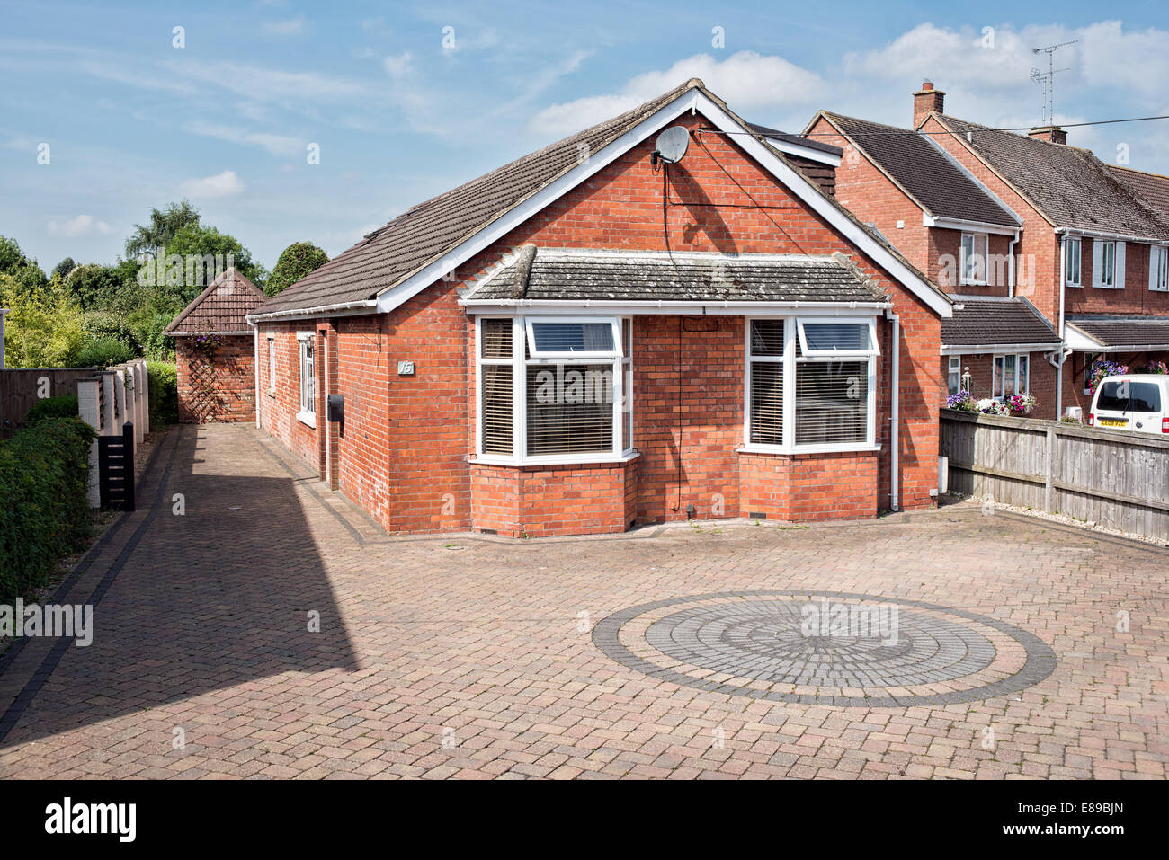 A renovated & extended, double glazed, red brick bungalow with block paved forecourt  on a sunny day, Wiltshire, UK Stock Photo