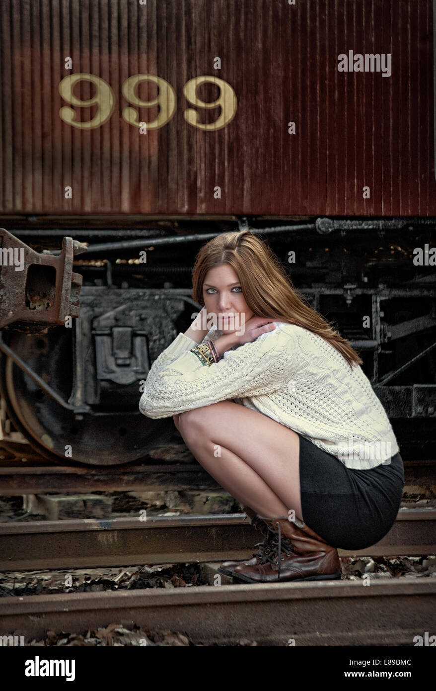 Young female by railroad track and train. Stock Photo