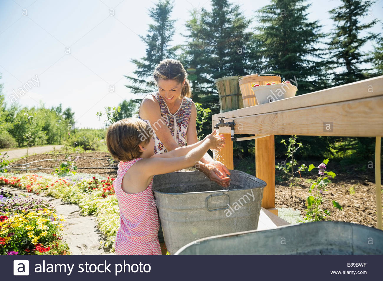 Mother and daughter washing hands in garden Stock Photo