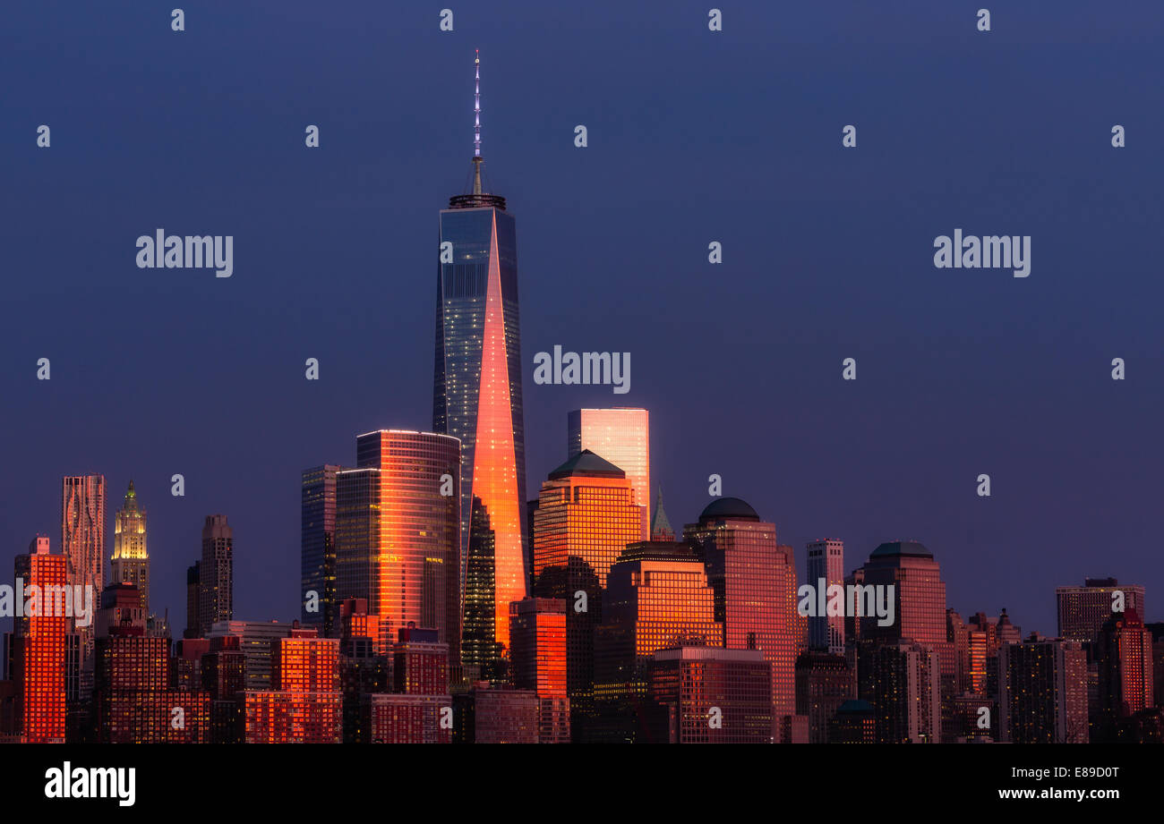 One World Trade Center commonly referred to as the Freedom Tower and other Financial District skyscrapers are bathed in golden light during the last light at sunset. Stock Photo