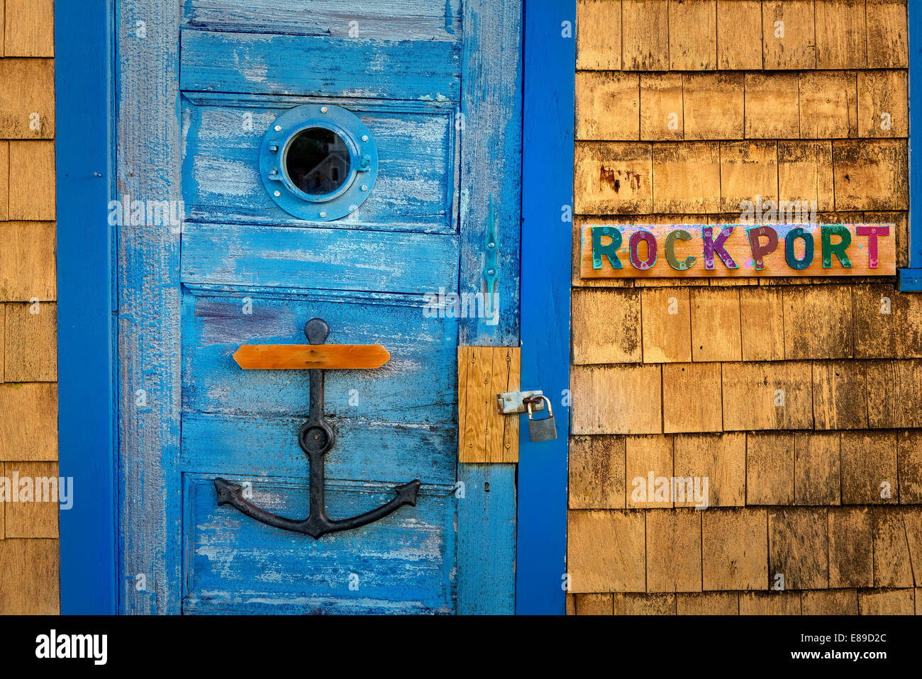 Colorful wooden shakes (shingles) hut's door with nautical window, anchor and Rockport sign, at Bradley Wharf coined Motif Number One in Rockport, Massachusetts. Stock Photo