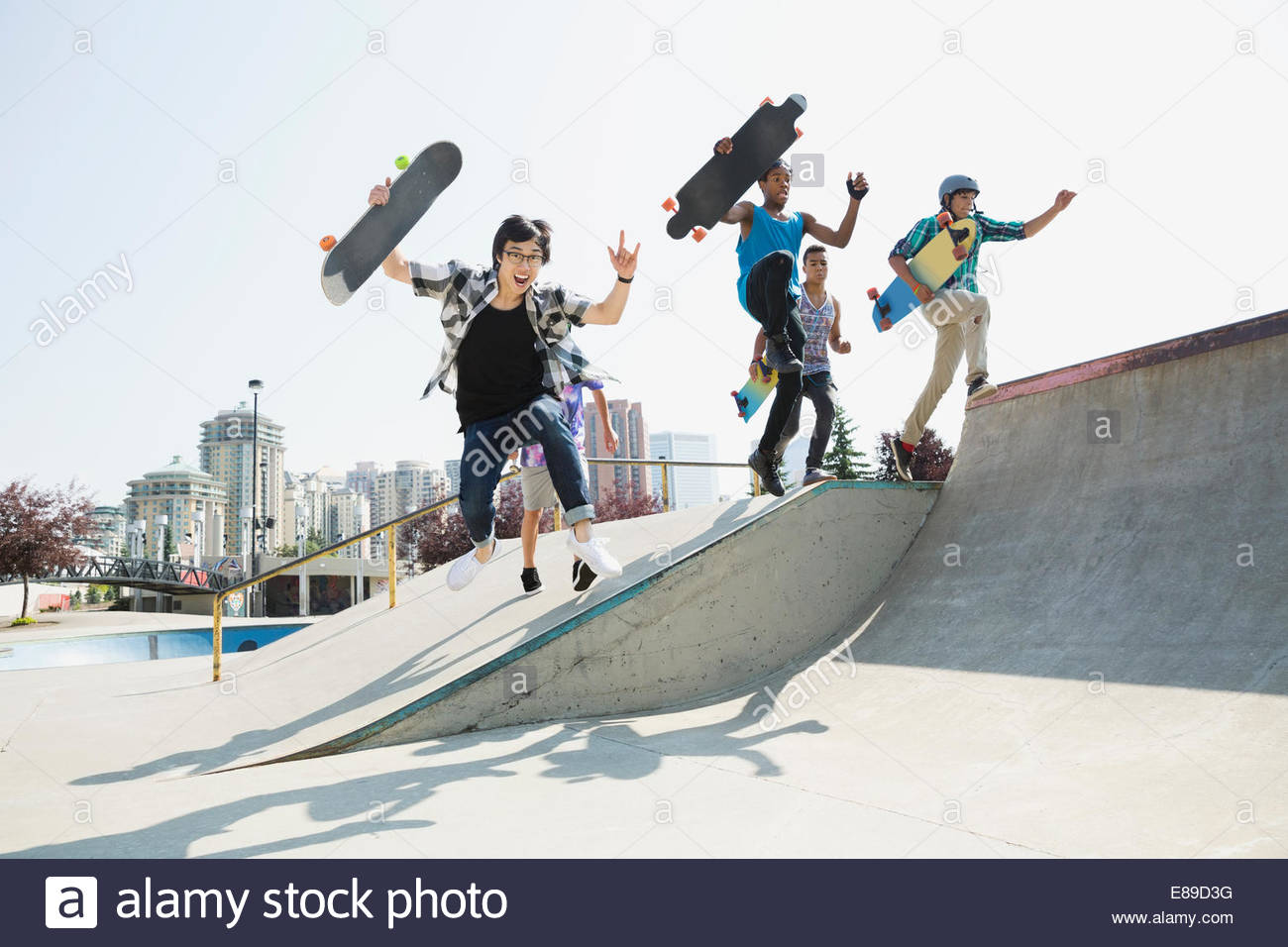 Teenage boys with skateboards jumping off ramp Stock Photo Alamy