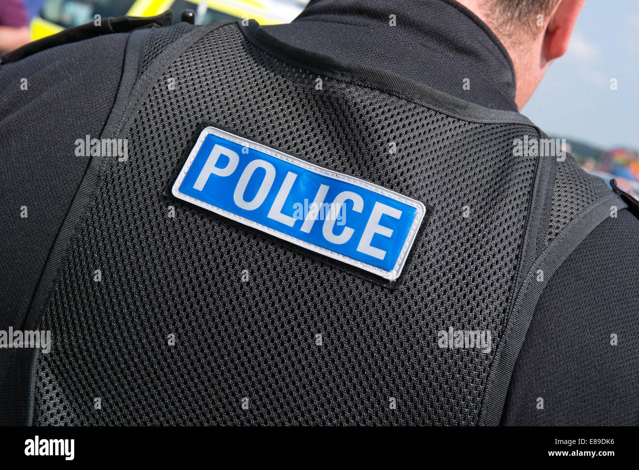 A caucasian British male policeman wearing modern police uniform with the word police stitched  on the back of his tactical vest Stock Photo