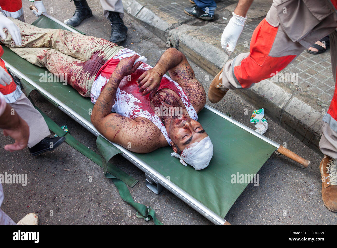 Shiite Muslim man, covered in his own blood, receiving medical attention after fainting, on Ashura Day in Nabatieh, Lebanon. Stock Photo