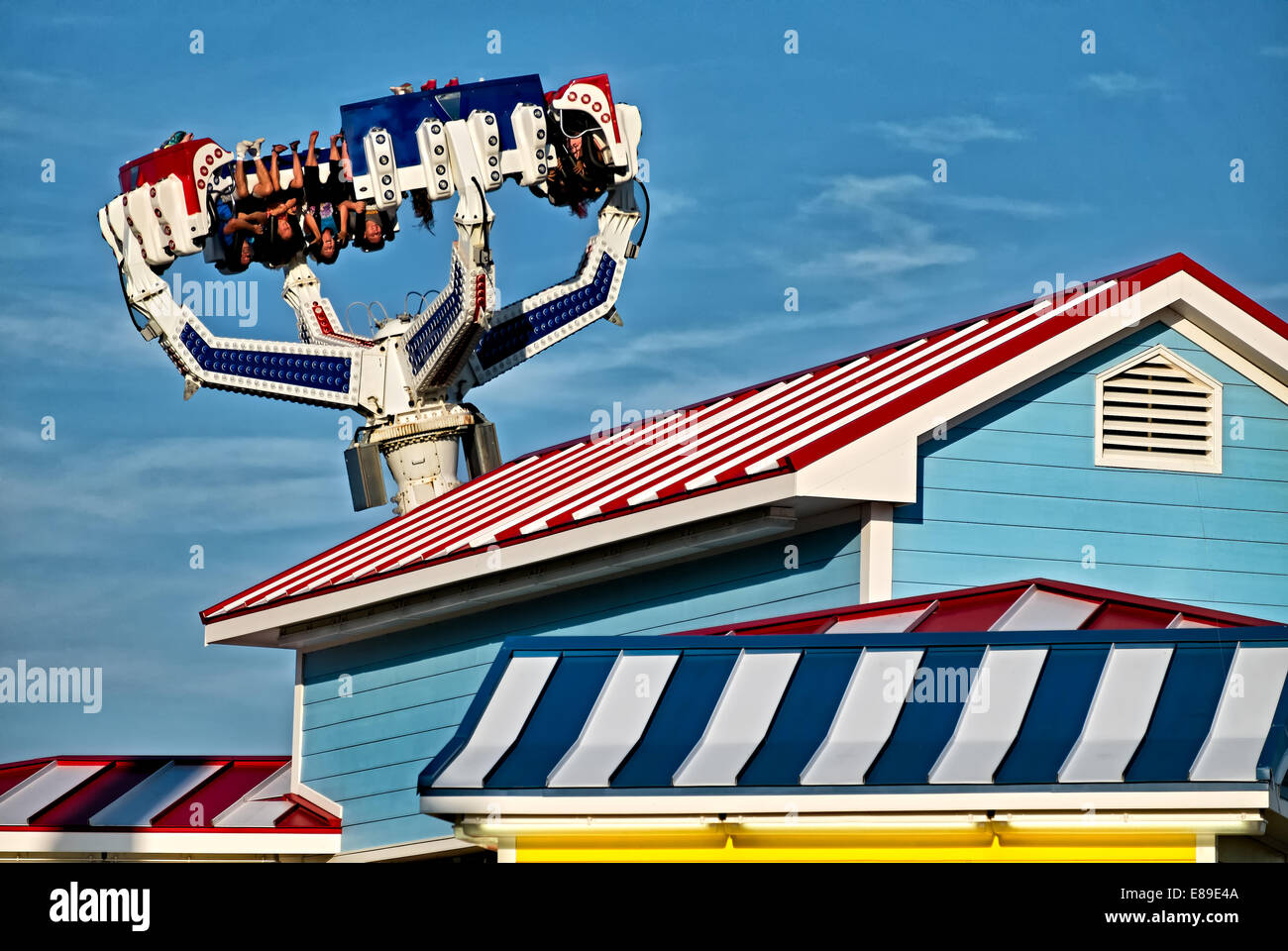 Colorful striped structures along with thrill chasers upside down on board the latest ride of Casino Pier the 'Super Storm'. Stock Photo