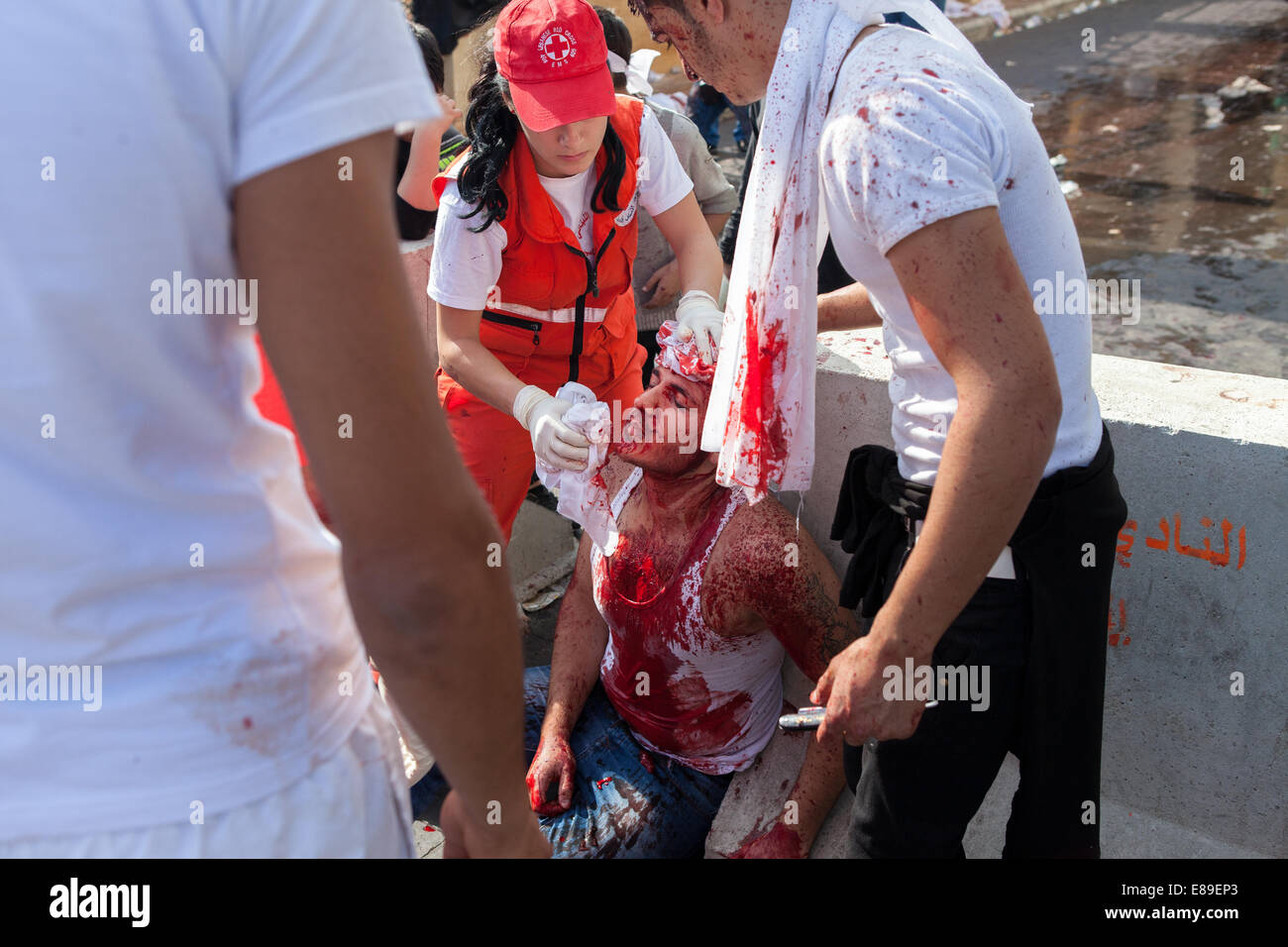 Shiite Muslim man, covered in his own blood, receiving medical attention, on Ashura Day in Nabatieh, Lebanon. Stock Photo