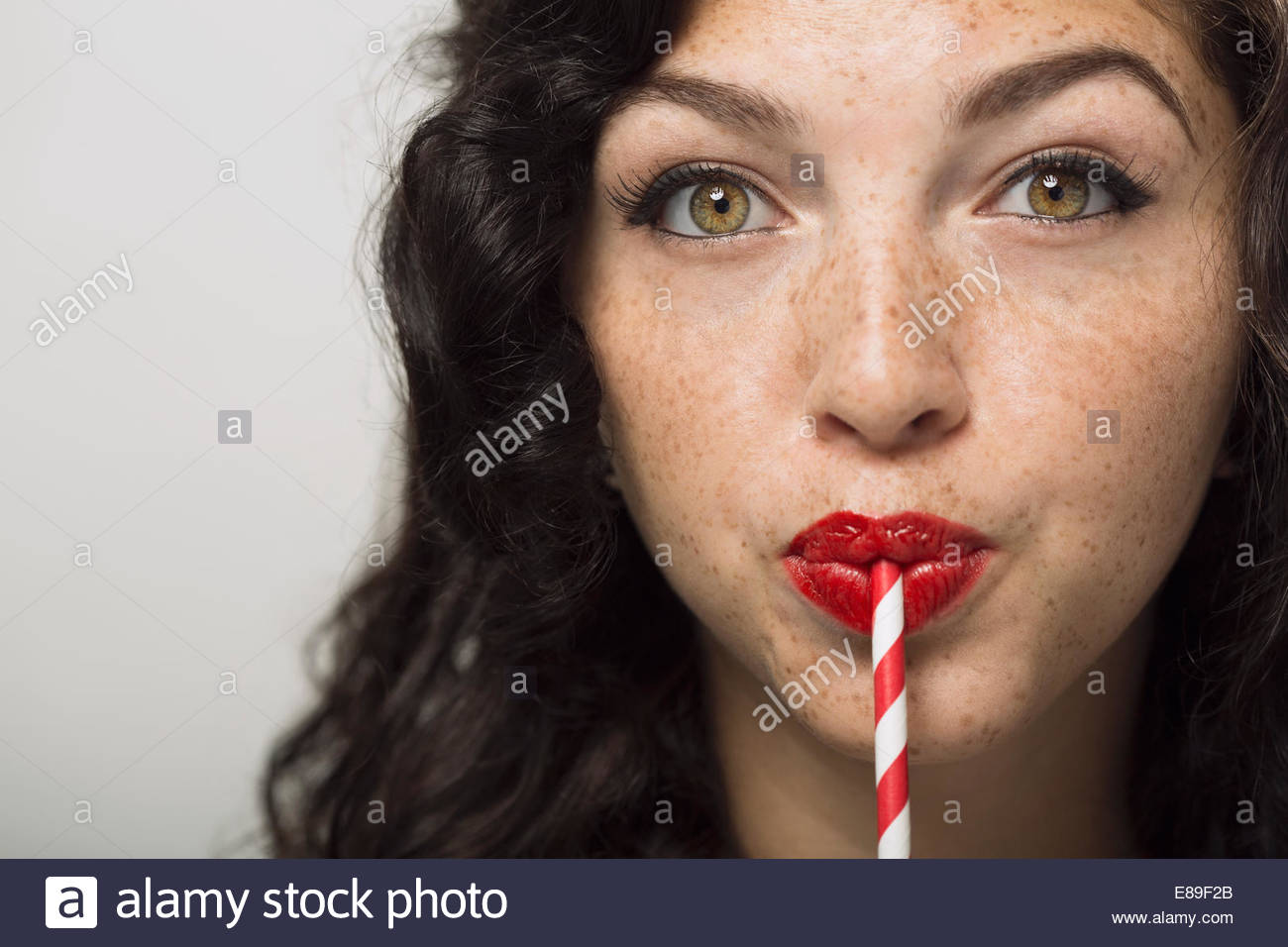 Portrait of woman with freckles drinking from straw Stock Photo