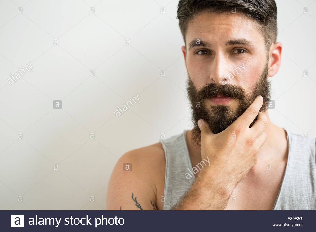 Close up portrait of serious man rubbing beard Stock Photo