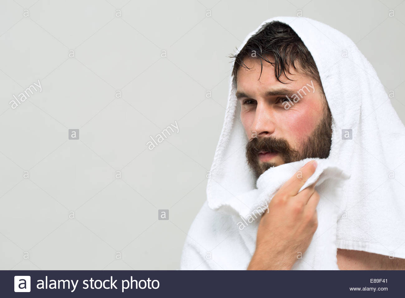 Brunette man drying beard with towel Stock Photo