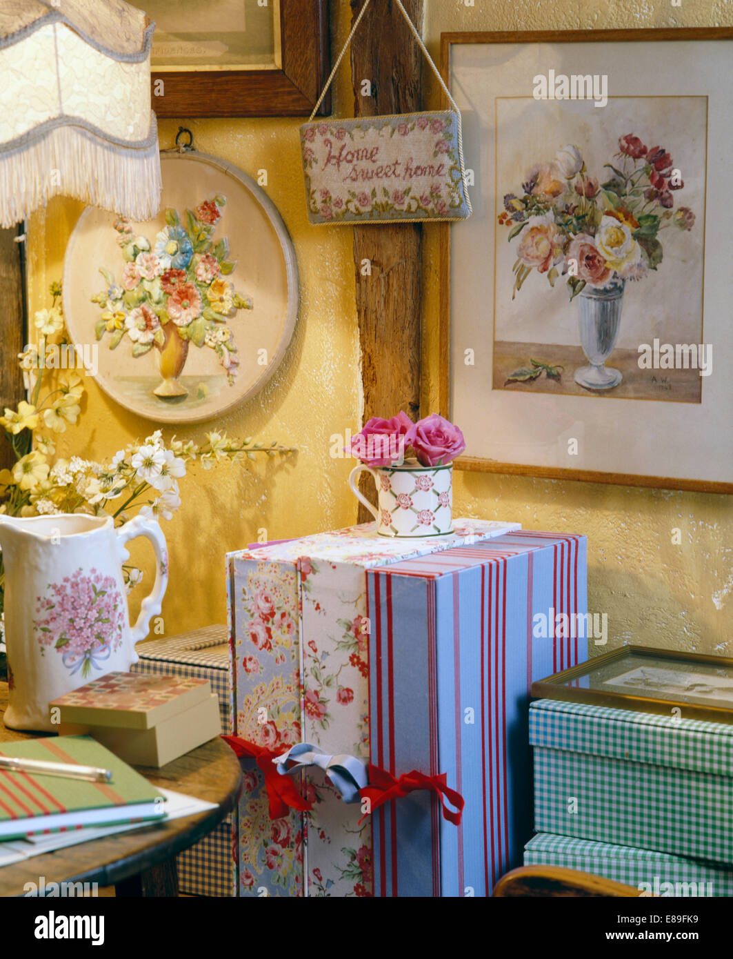 Close-up of floral pictures and Home Sweet Home" on wall above floral fabric covered storage boxes Stock Photo