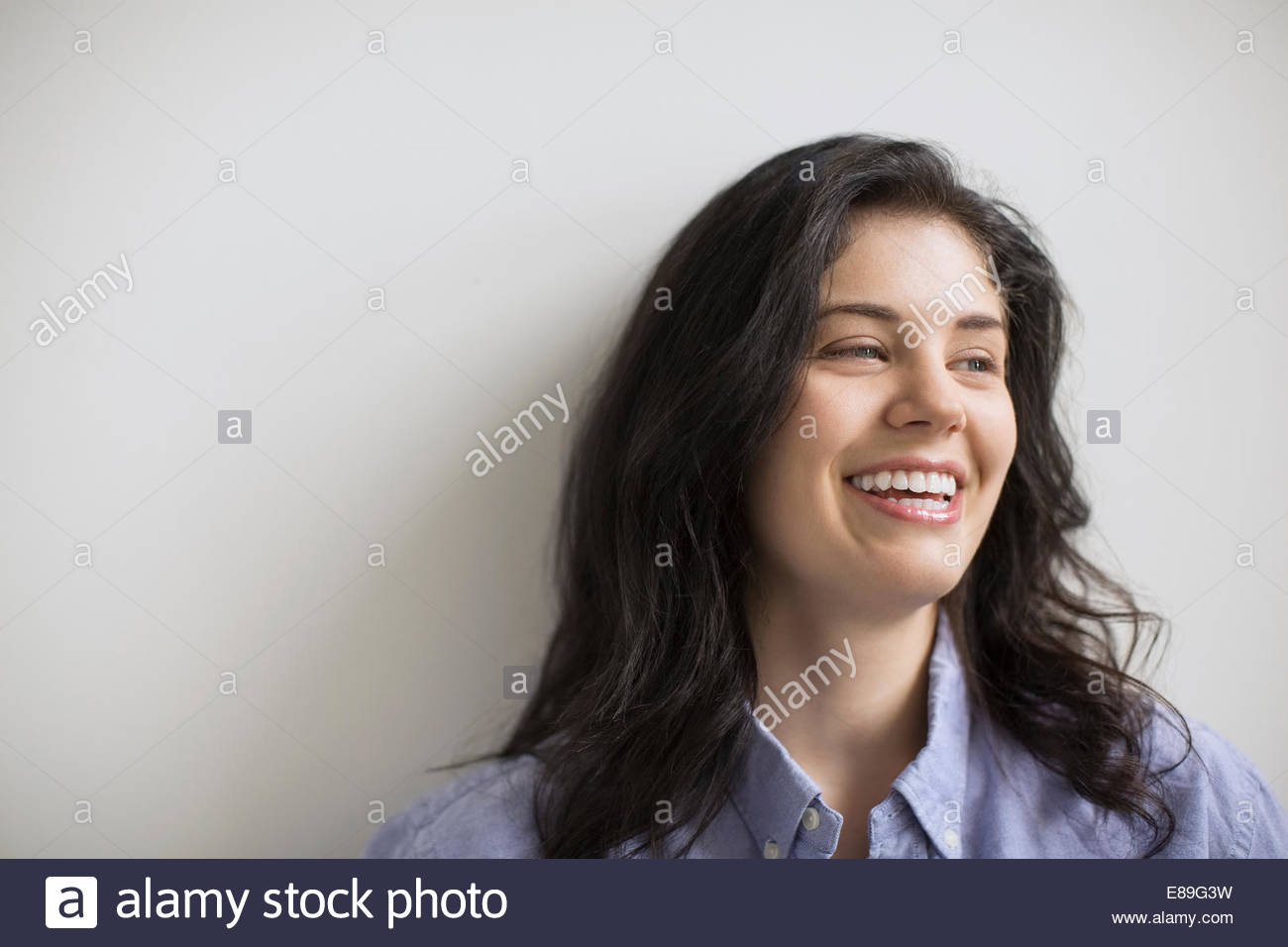 Woman with black hair laughing and looking away Stock Photo - Alamy