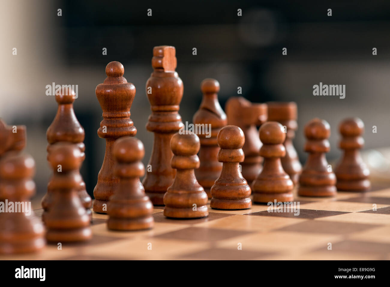 Wooden chess pieces facing off, across the games board during a match Stock Photo