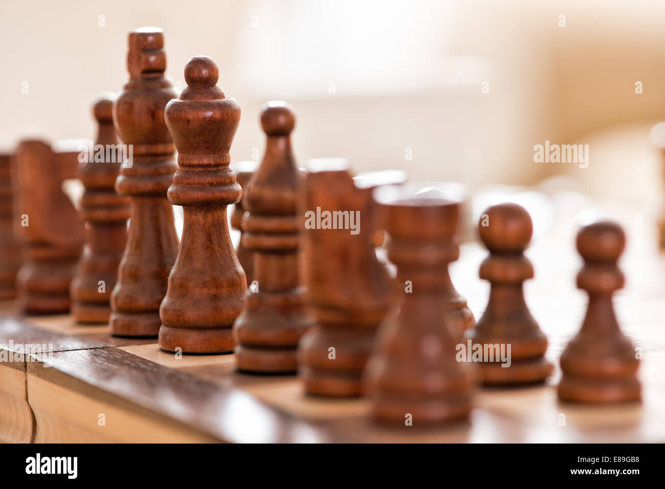 Wooden chess pieces facing off, across the games board during a match Stock Photo