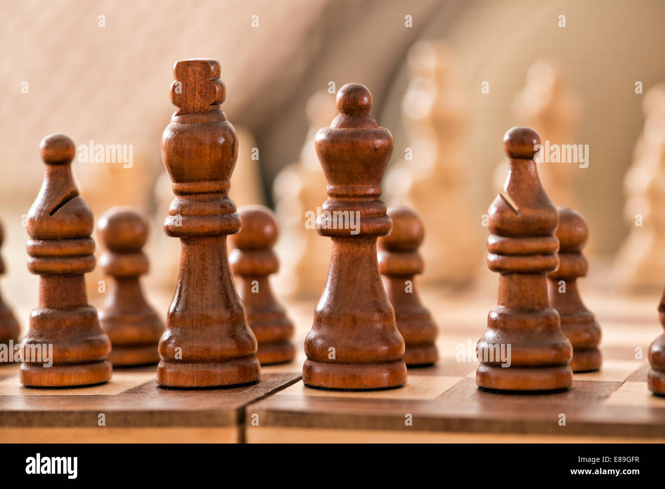 Wooden chess pieces facing off, across the games board during a match Stock Photo