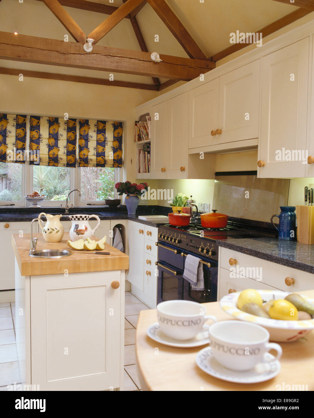 Small sink in island unit in country kitchen with window blind and
