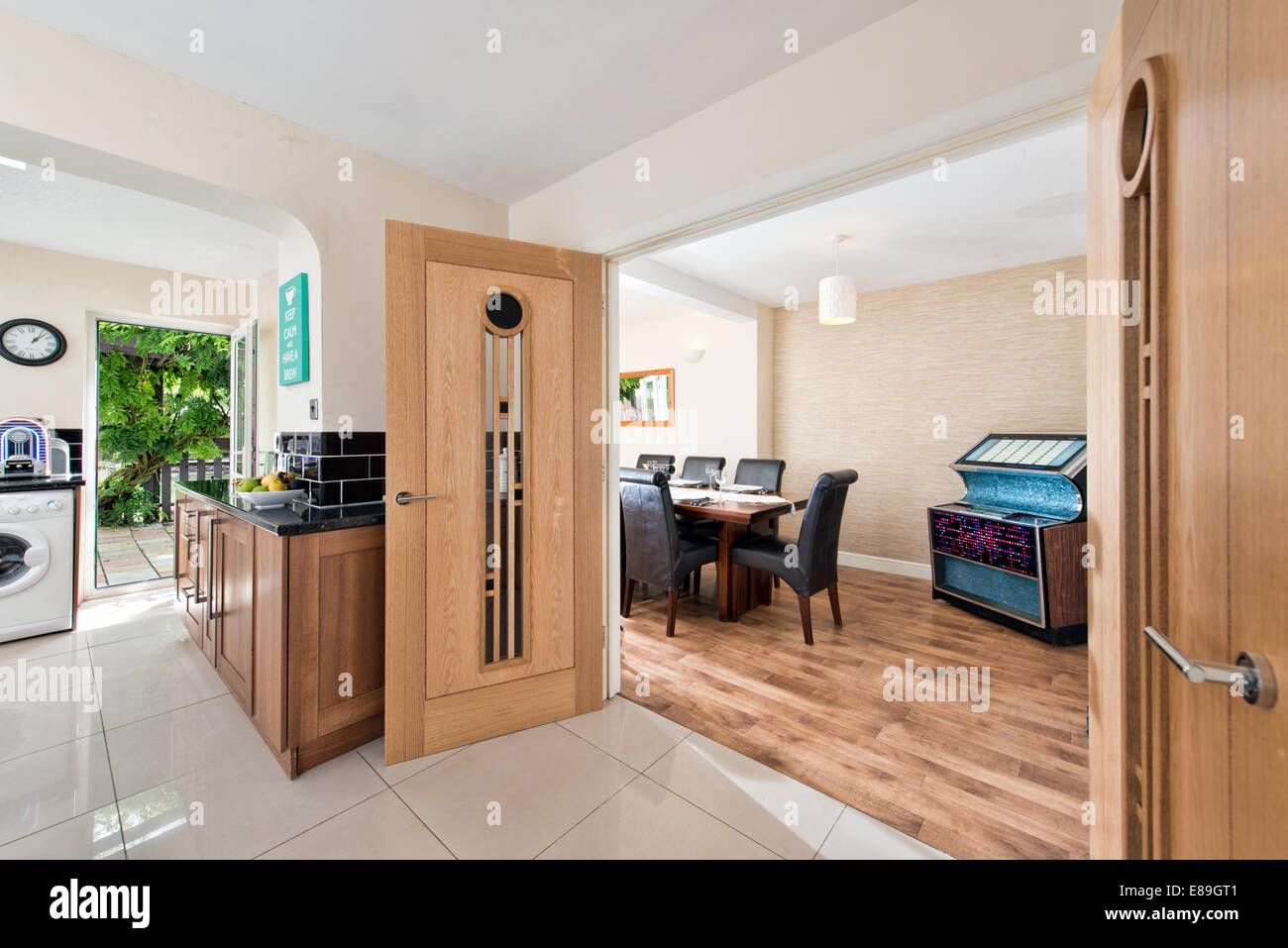 A view through double, solid wood doors from a kitchen in to a dining room in an extended & renovated home, UK Stock Photo