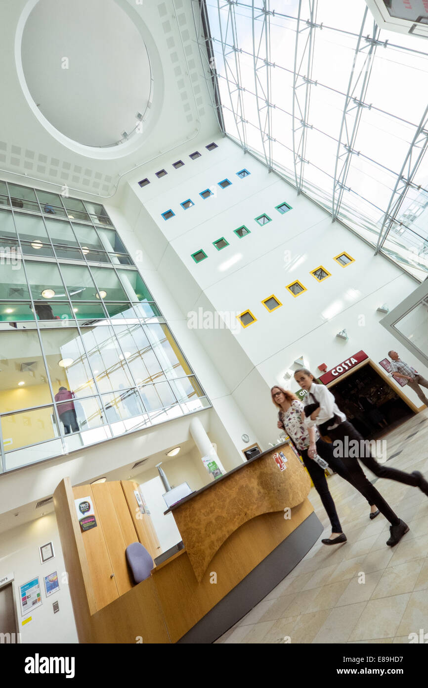 Visitors walking by the reception desk in the entrance lobby  to the NHS trust, great western hospital in Swindon, Wiltshire, UK Stock Photo