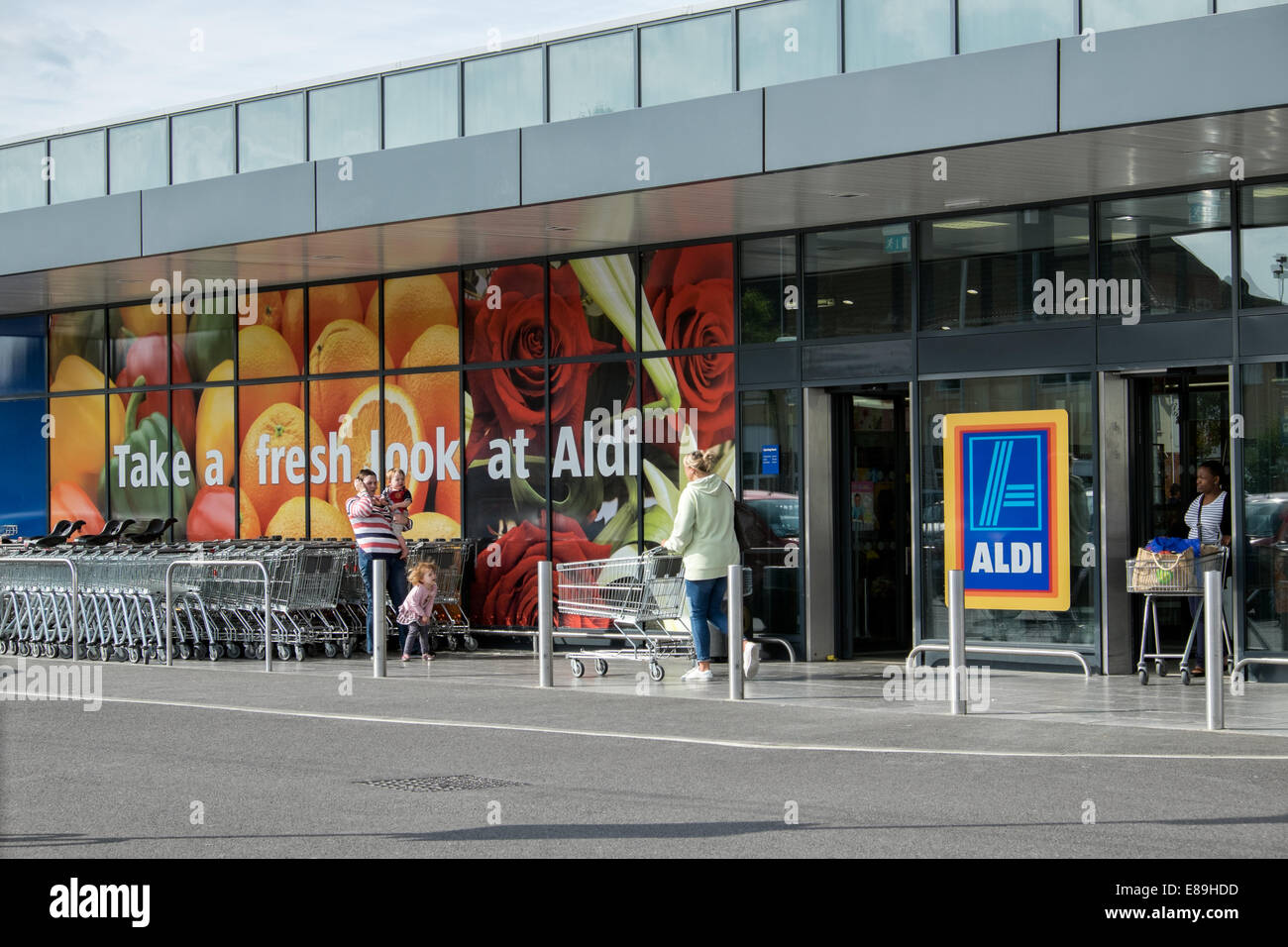 Customers & shopping carts outside German discount supermarket, Aldi in Swindon, Wiltshire, UK Stock Photo