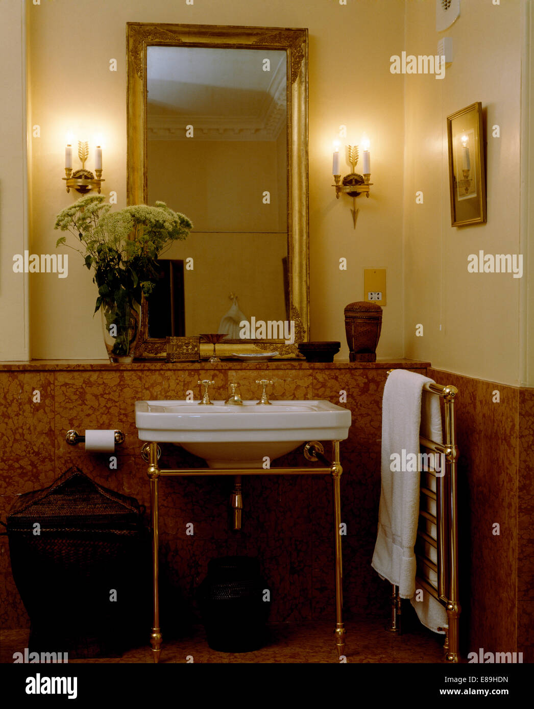 Wall lights on either side of rectangular gilt mirror above basin on gilt  stand in townhouse bathroom with tiled dado Stock Photo - Alamy