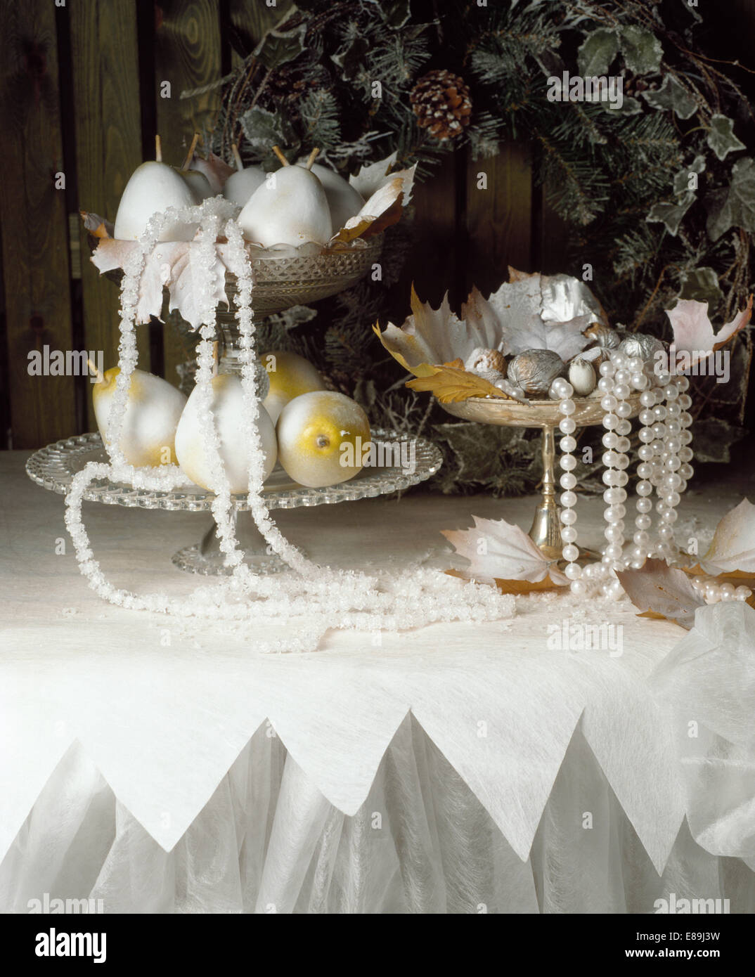 Close up of strings of pearls and silver pears on silver dishes on white and silver tablecloth Stock Photo