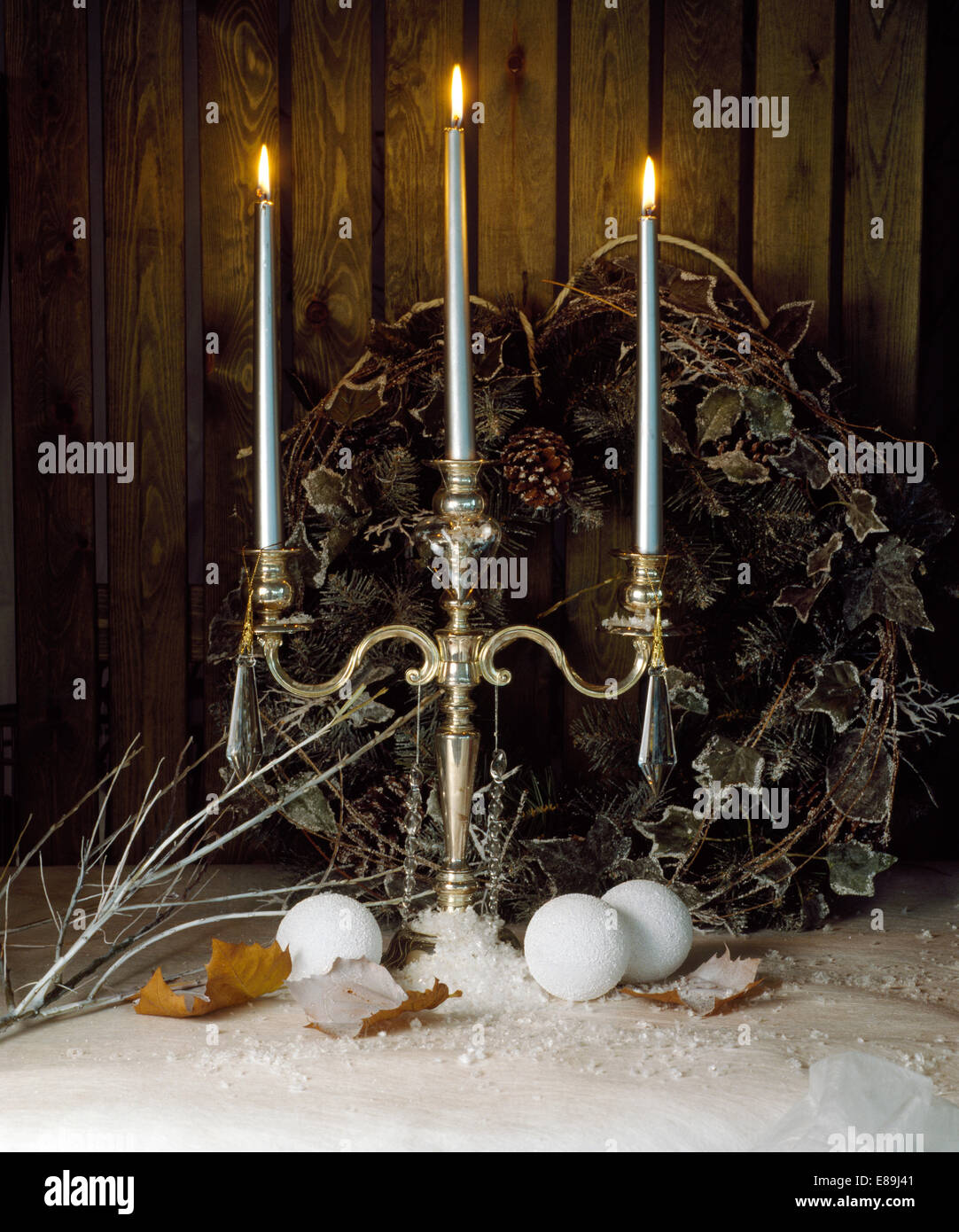 Christmas still-life of silver candelabra with lighted silver candles on table with frosted ivy and conifer wreath Stock Photo