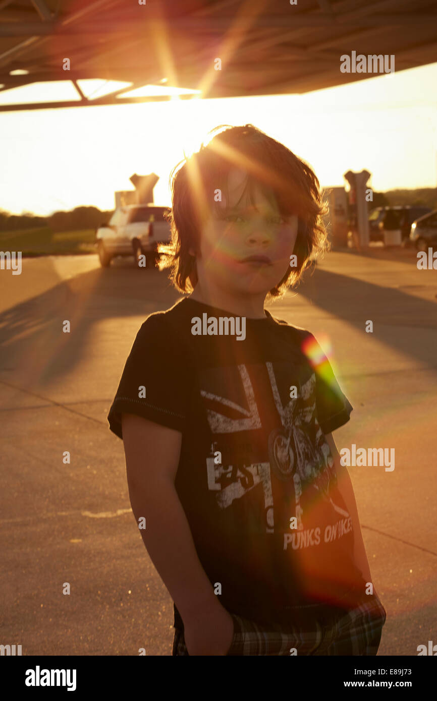 Boy standing at gas station at sunset Stock Photo