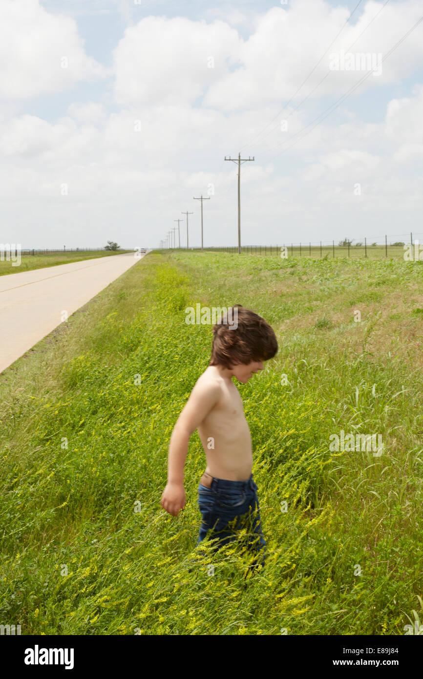 Boy walking in grass in countryside Stock Photo