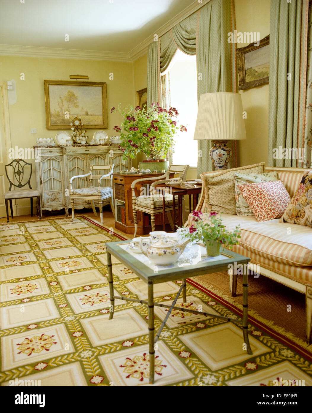 Floral carpet in drawing room with striped Georgian style sofa and small coffee table Stock Photo