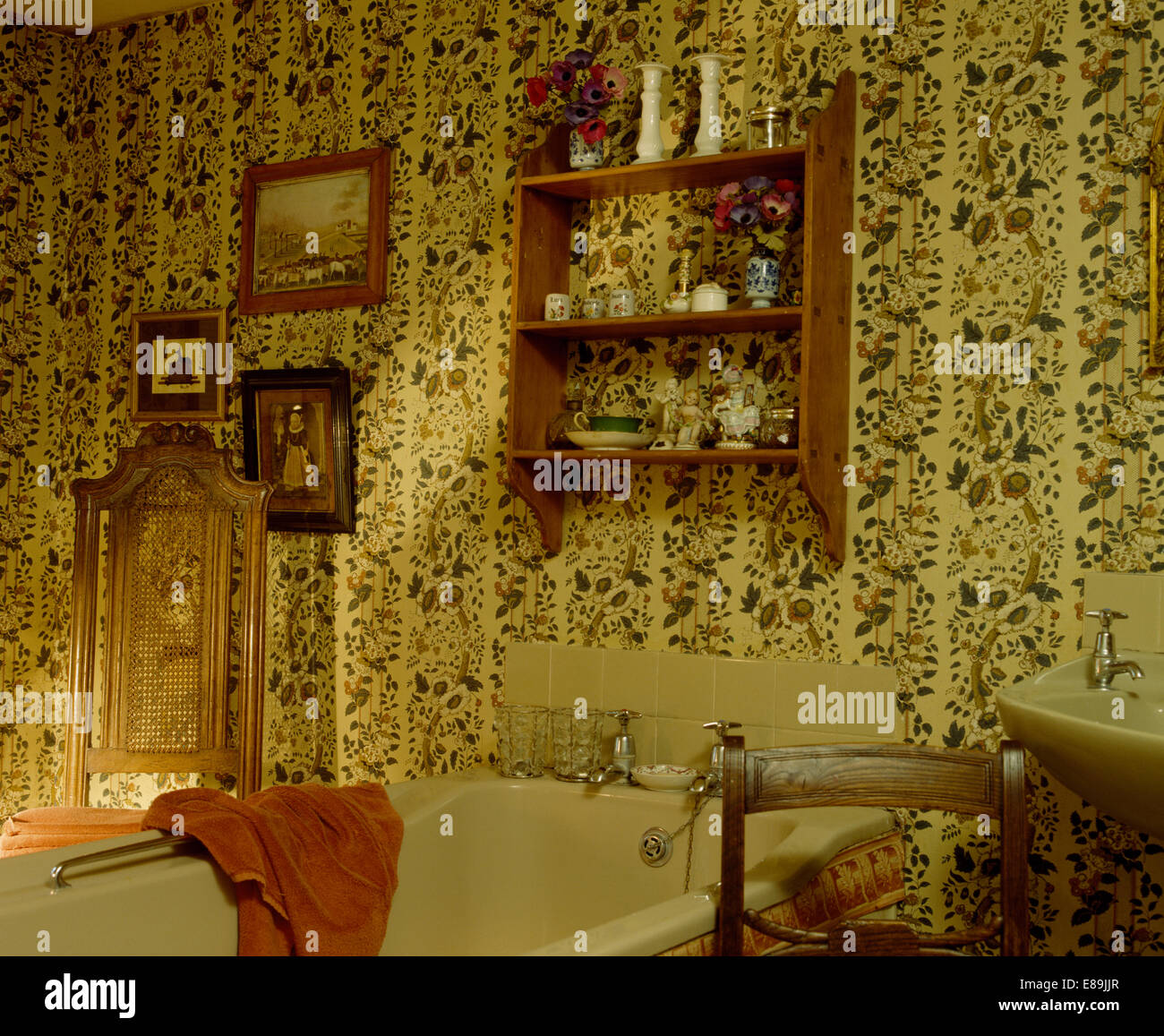 Small pine shelf unit above beige bath in country bathroom with floral