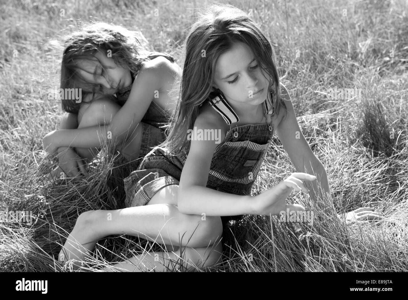 Girls in overalls in field of tall grass Stock Photo