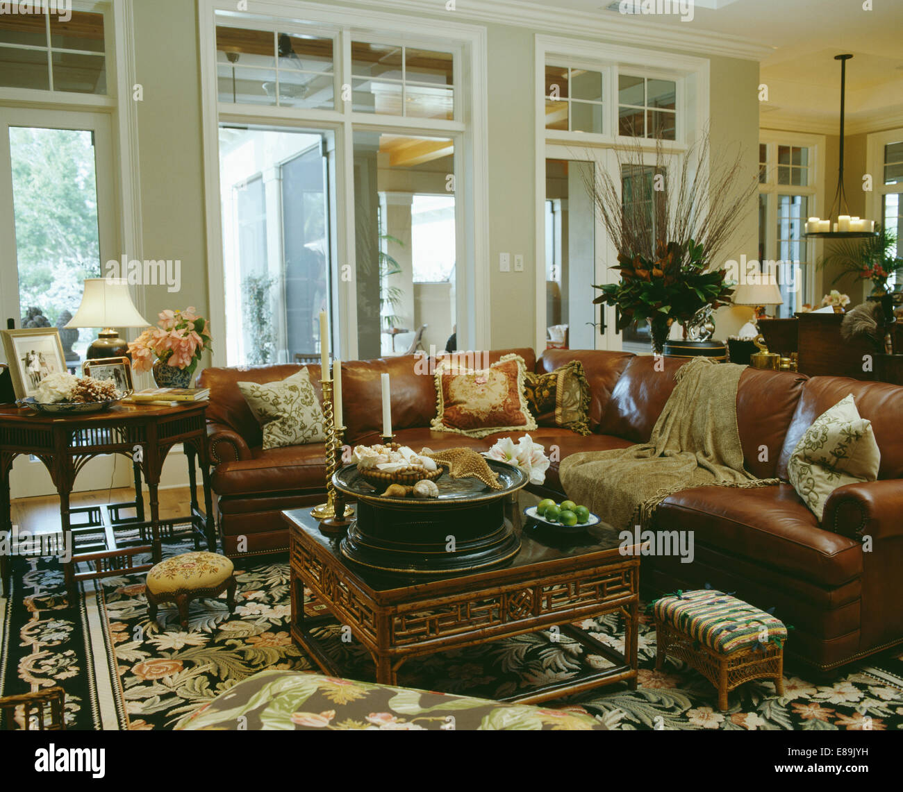 Oriental-style coffee table in front of large brown leather corner sofa in traditional living room with patterned carpet Stock Photo
