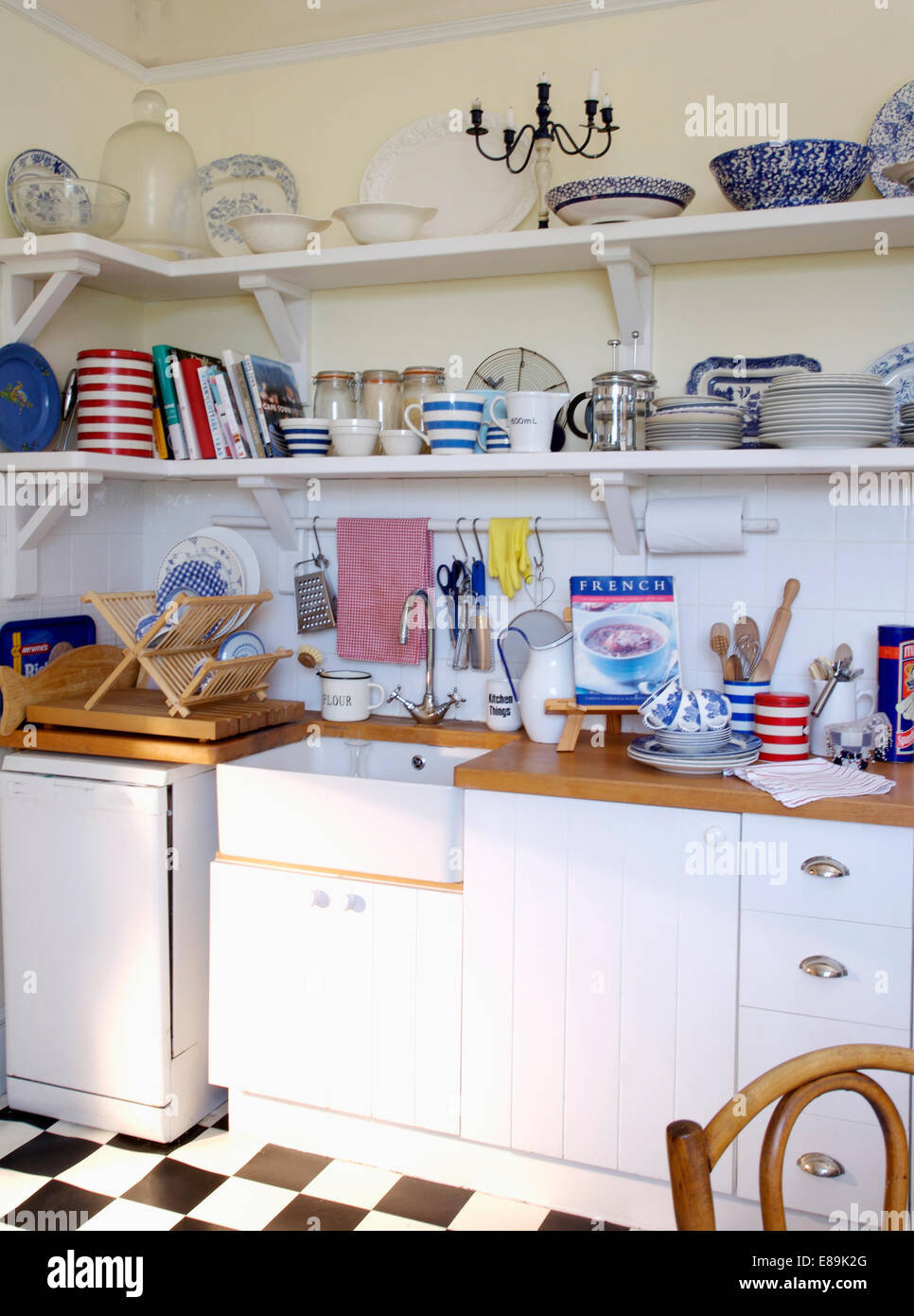 https://c8.alamy.com/comp/E89K2G/crockery-on-shelves-above-white-ceramic-sink-in-white-country-kitchen-E89K2G.jpg