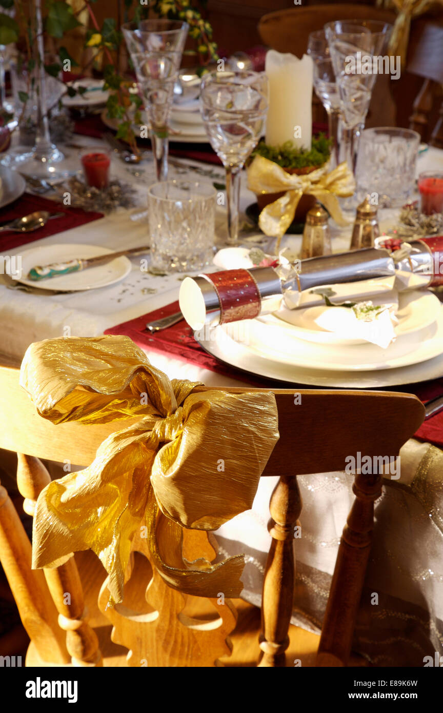 Metallic gold bow on chair at table decorated for Christmas Stock Photo