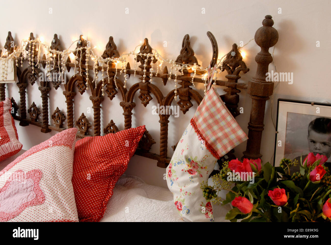Close-up of cushions and cotton Christmas stocking bed with Gothic-style headboard and Christmas lights Stock Photo