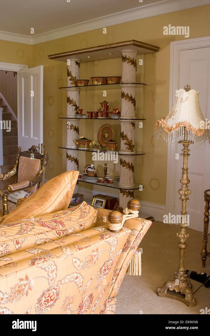Gilt standard lamp and classical pillared shelves in living room with Knole sofa Stock Photo