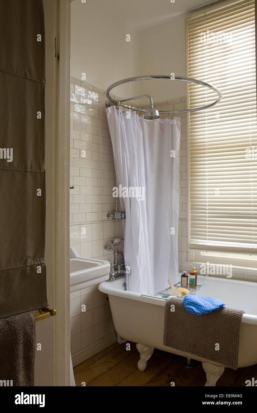 Shower above old fashioned roll top bathtub in traditional bathroom