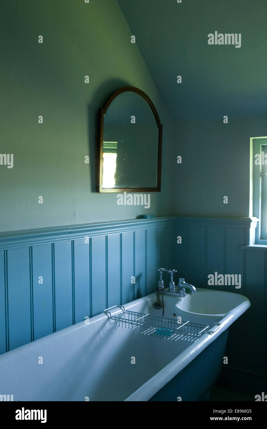 Blue tongue+groove panelling above roll top bath in country bathroom Stock Photo