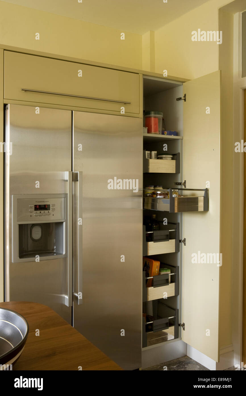 https://c8.alamy.com/comp/E89MJ1/stainless-steel-american-style-fridge-beside-open-larder-cupboard-E89MJ1.jpg