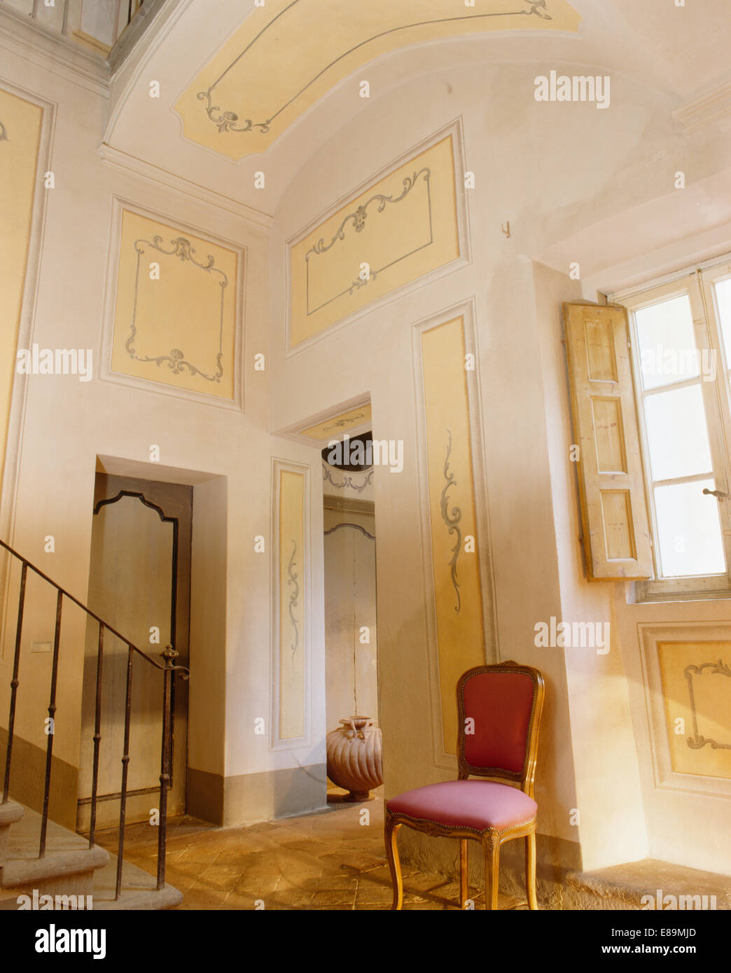Decoratively painted panels on walls of high ceilinged Tuscan hall with ...