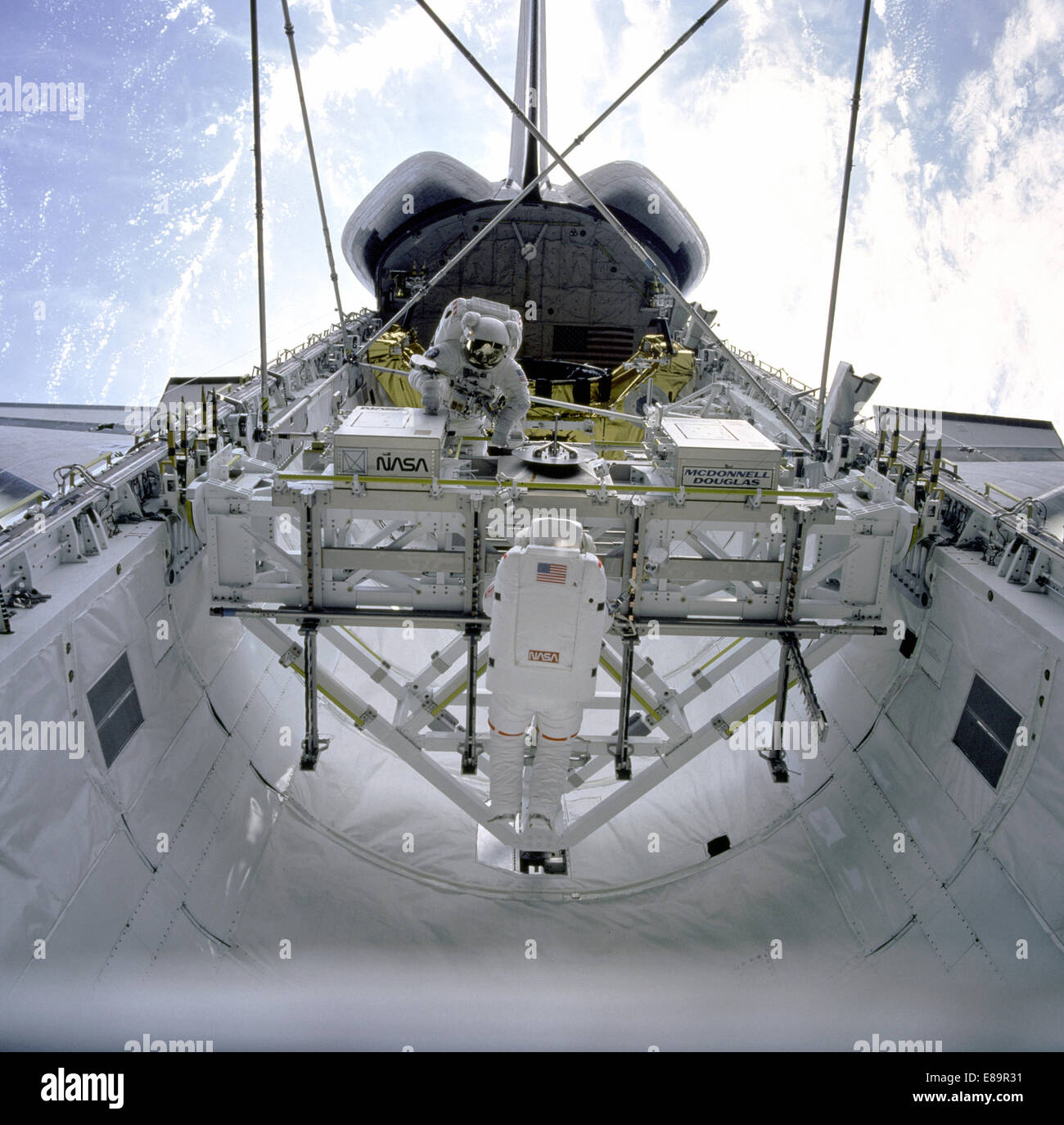 STS-49 Mission Specialist (MS) Kathryn C. Thornton (foreground) releases a strut from the Multipurpose Experiment Support Structure (MPESS) strut dispenser during Assembly of Station by Extravehicular Activity Methods (ASEM) procedures in Endeavour's payload bay. MS Thomas D. Akers, positioned on the opposite side of the MPESS, waits for Thornton to hand him the final strut. The two astronauts are building the ASEM structure during the mission's fourth EVA. The ASEM structure, locked in at four corners to payload retention latch assemblies (PRLAs), rises above the payload bay. In the backgroun Stock Photo