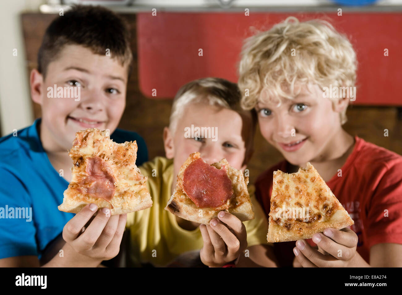 Three boys holding slices of pizza Stock Photo