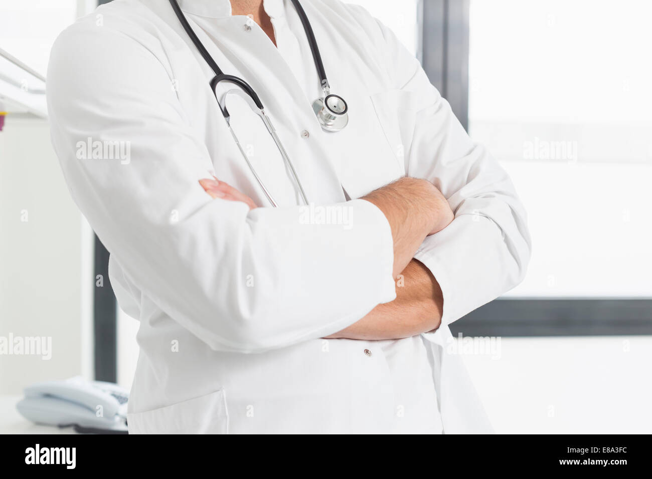 Doctor holding arms crossed, mid section Stock Photo