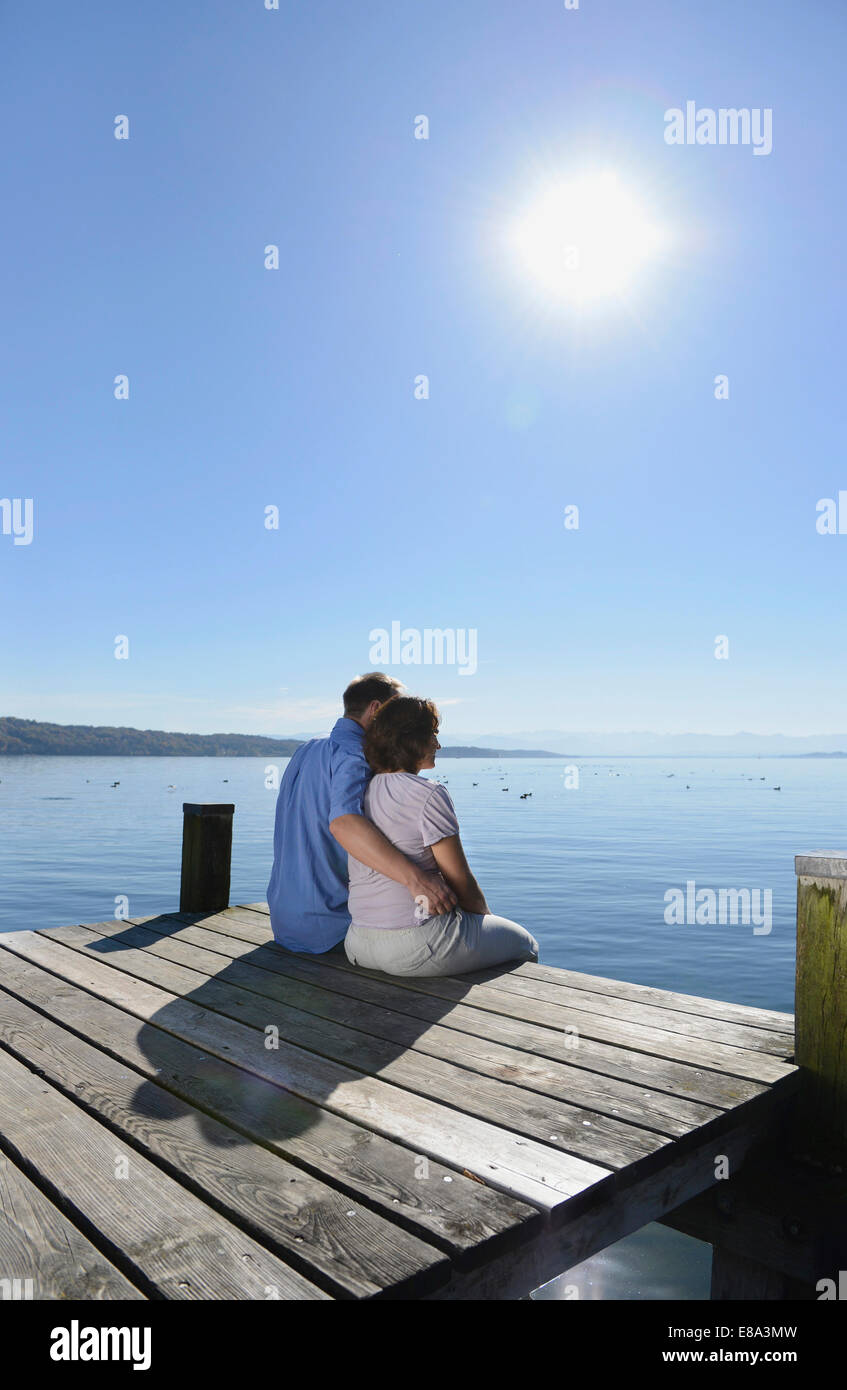 Mature couple sitting and embracing each other on boardwalk, Bavaria, Germany Stock Photo