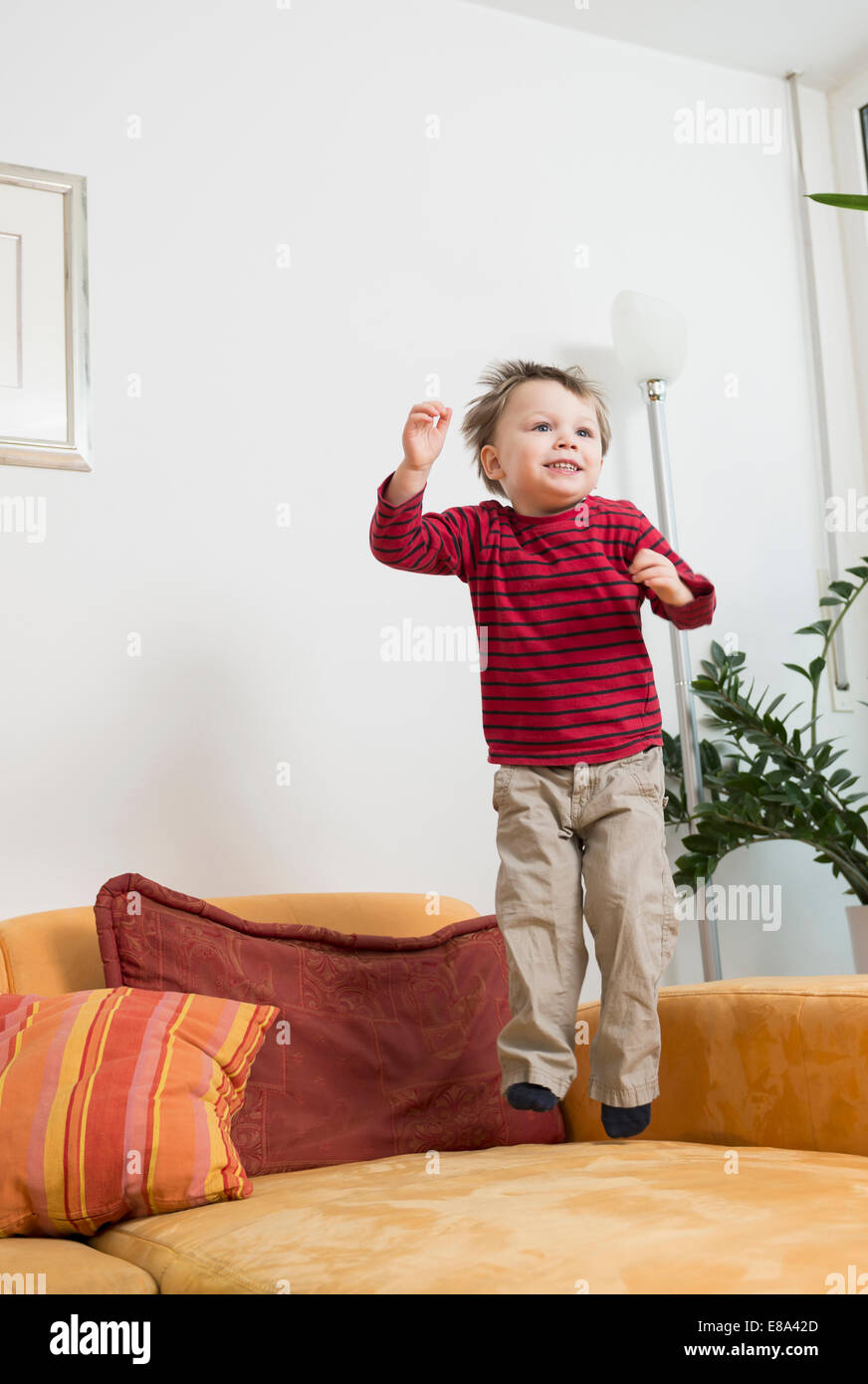 Boy jumping on couch, smiling Stock Photo Alamy