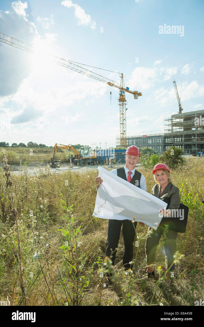 Architects with construction plan inspecting site Stock Photo - Alamy