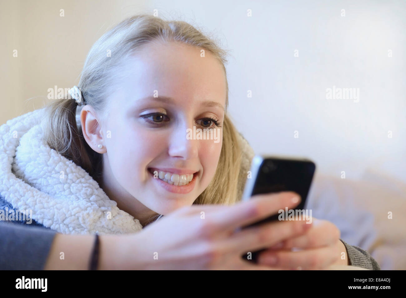 Teenage girl using smart phone on couch, smiling Stock Photo - Alamy